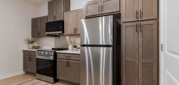 A kitchen with a stainless steel refrigerator and wooden cabinets.