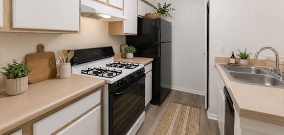 A kitchen with a black refrigerator and a white stove top oven.