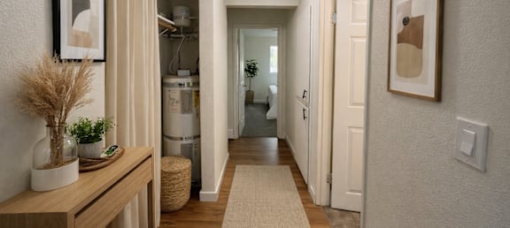 A hallway with a wooden bench and a rug on the floor.