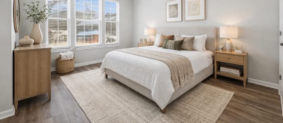 A bedroom with a large bed and a window with blinds.
