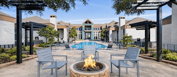 A fire pit sits in the middle of a patio with chairs around it.