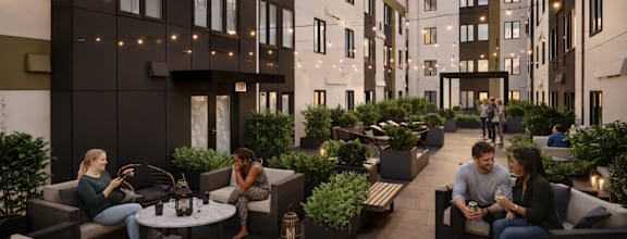 A group of people are sitting and talking in a courtyard surrounded by buildings.