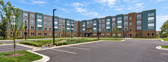 A large parking lot in front of a multi-story apartment building.