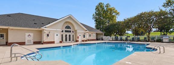 A swimming pool in front of a building with a clear blue sky.