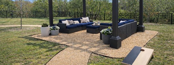 A black pergola with lights and a couch under it.