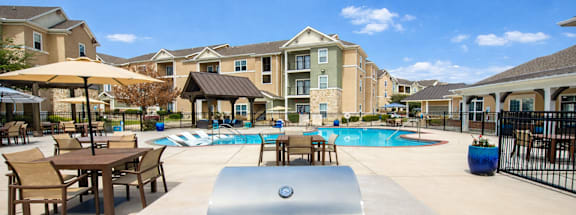 A large outdoor grill is in the middle of a pool surrounded by chairs and umbrellas.