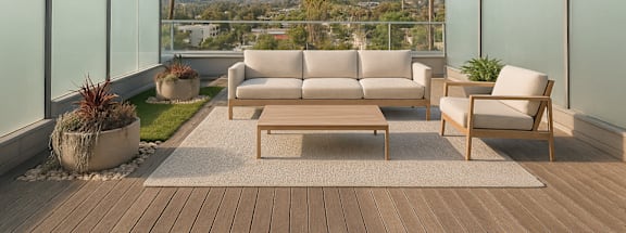A patio with a couch, chairs, and a table with a view of the mountains at Fusion Hollywood.