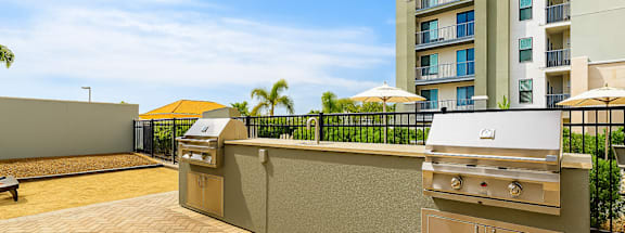 A barbecue grill is on a patio in front of a building.