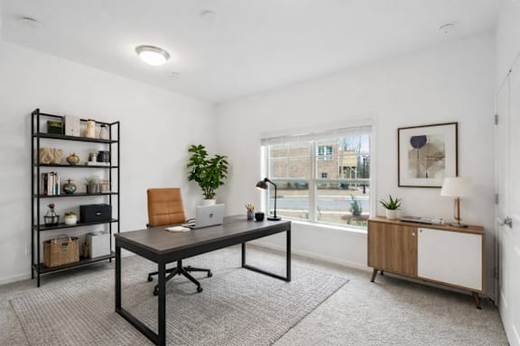 A room with a desk, chair, and shelves with various items.