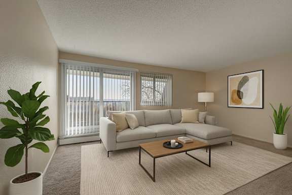 An empty white living room with a kitchen in the corner at Cedar Gardens Apartments. 