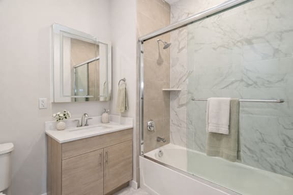 A bathroom with a marble wall and a glass shower door.