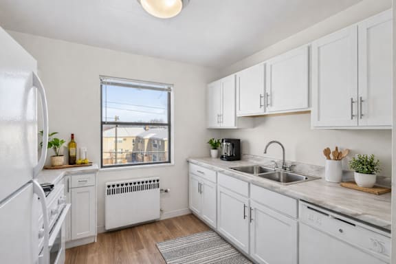 A kitchen with white cabinets and a window overlooking buildings.