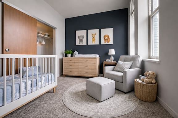 A nursery room with a crib, a chair, a table, and pictures on the wall.