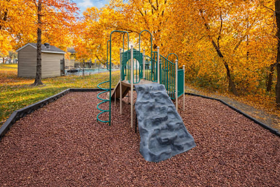 A playground with a slide and a grey tarp on the ground.