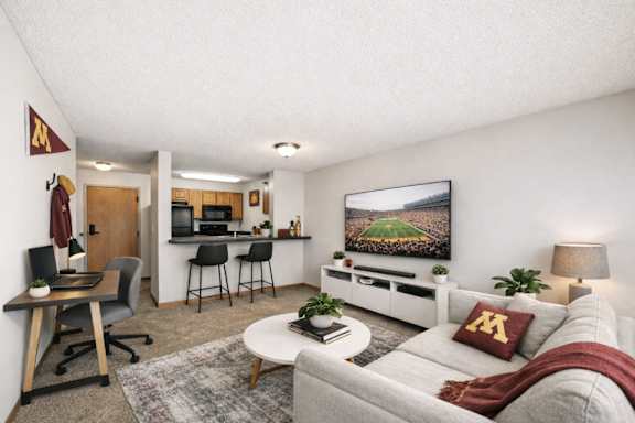 A living room with a grey couch, a wooden desk, and a television.