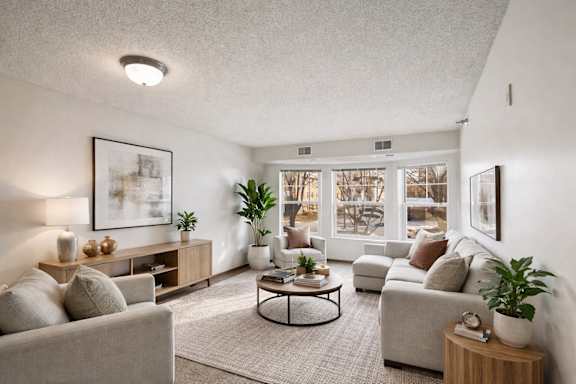 A living room with a grey couch, a coffee table, and a large window.