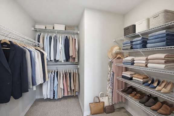 A well-organized walk-in closet with neatly arranged clothes and shoes.
