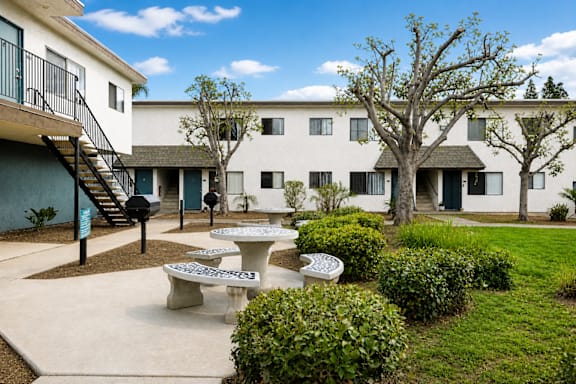 A courtyard with tables and chairs surrounded by buildings.
