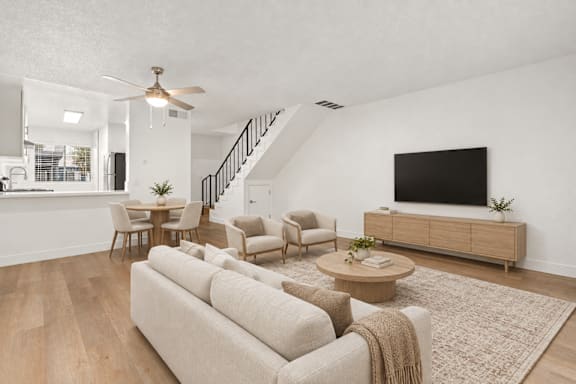 A living room with a beige couch, a coffee table, and a flat-screen TV.