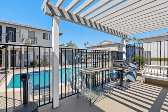 A pool area with a white pergola and black fence.