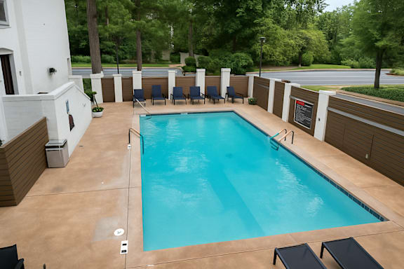 A rectangular pool with a brownish tiled floor and a white wall with a black sign on it.