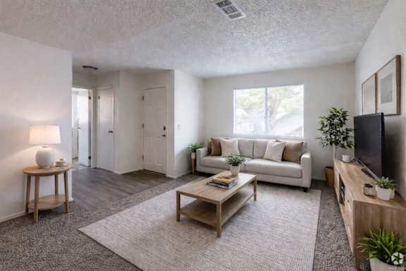 A living room with a white couch, a wooden coffee table, and a flat-screen TV.