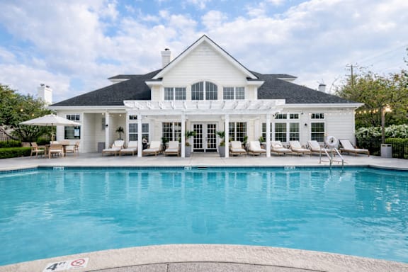 A large white house with a pool in front.
