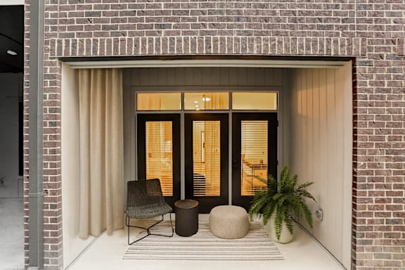 A chair, a table, and a plant are on a striped rug in front of a doorway.