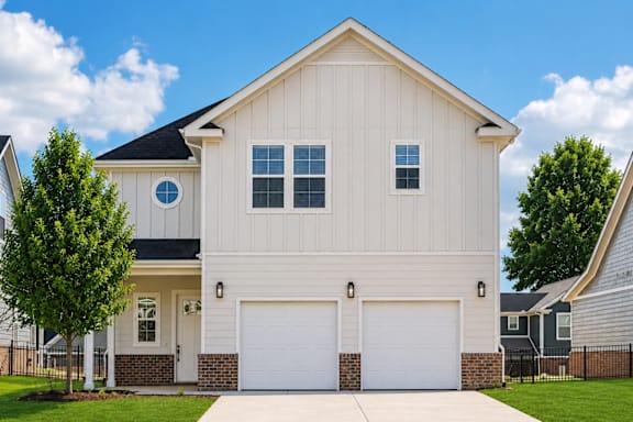 A white house with a black roof and two garages.