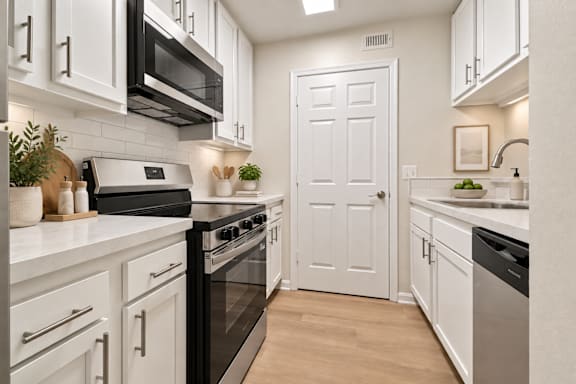 A modern kitchen with a stainless steel refrigerator and grey cabinets.