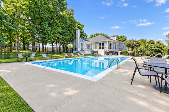 A pool with a table and chairs and a house in the background.