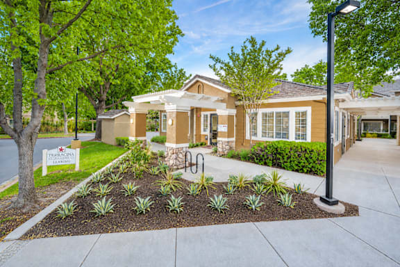 A well-maintained garden in front of a house with a sign that reads "The Enclave.".