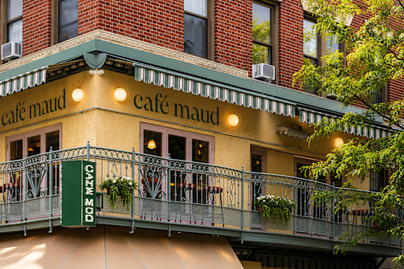 Cafe Maud is a cozy cafe with a balcony and hanging plants.