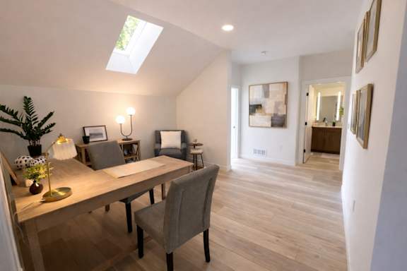 A room with a table and chairs and a skylight.