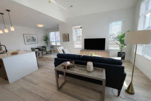A living room with a black couch and a wooden coffee table.