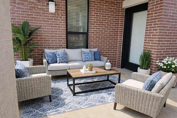 A patio with a sofa, two chairs, and a coffee table.