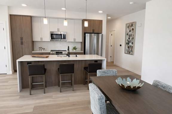 A modern kitchen with a wooden island and bar stools.