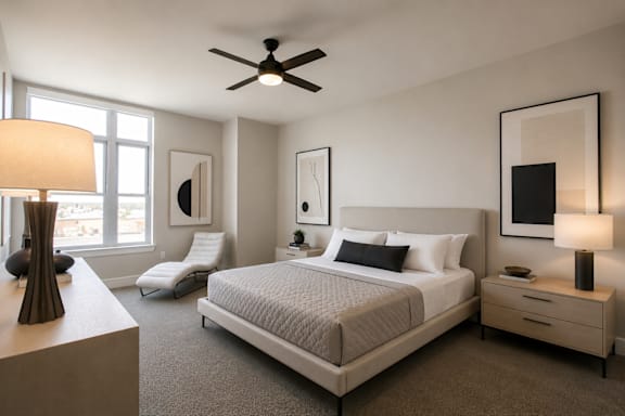 A bedroom with a large bed, a chair, and a ceiling fan.