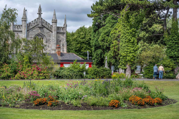 a garden with flowers and an old church in the background