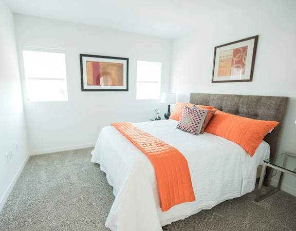 A bedroom with a bed, pillows, and a picture on the wall.