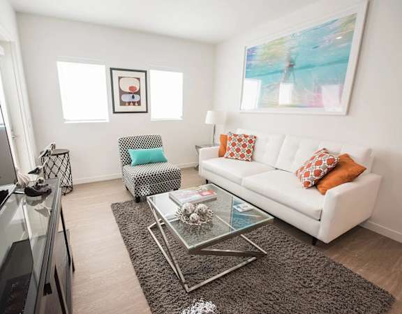A modern living room with a white couch and a glass coffee table.