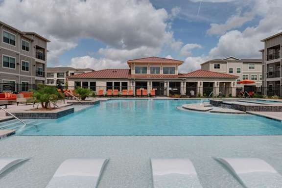 A large swimming pool in front of a building with a red roof.