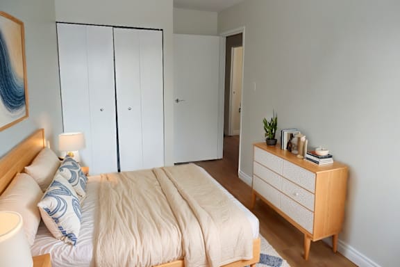 A bedroom with a bed, nightstand, and wardrobe.