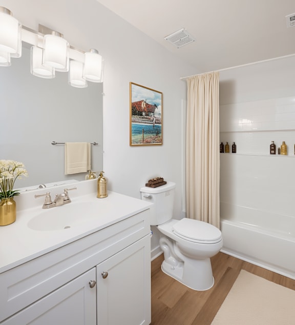A white toilet sits in a bathroom next to a sink and a bathtub.
