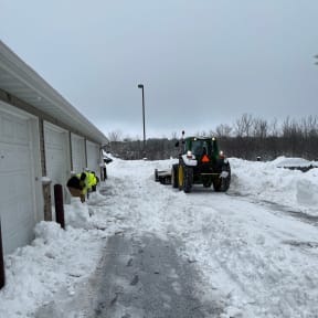 a tractor is parked in the snow next to a garage