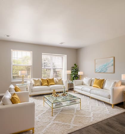 A living room with white furniture and a glass coffee table.