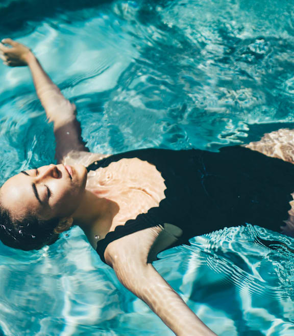 Woman Wearing Black Swimsuit Floating in Pool