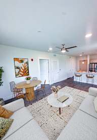 A living room with a white couch and a round table with a plant on it.