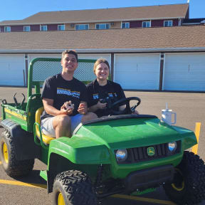 two people sitting on a green jeep in a parking lot