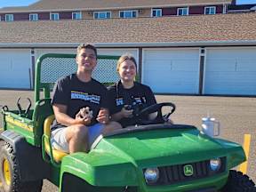 two people sitting on a green jeep in a parking lot